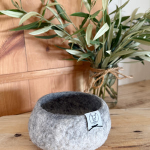 Alpaca fleece grey and white felted small bowl with plant in background.