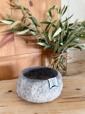 Alpaca fleece grey and white felted small bowl with plant in background.