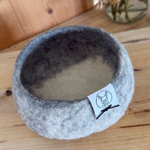 Alpaca fleece grey and white felted small bowl with plant in background.
