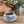 Felted bowl with a label on a wooden surface, next to a plant.