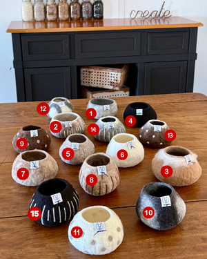 Assorted decorative felted bowls on a wooden table with numbered labels